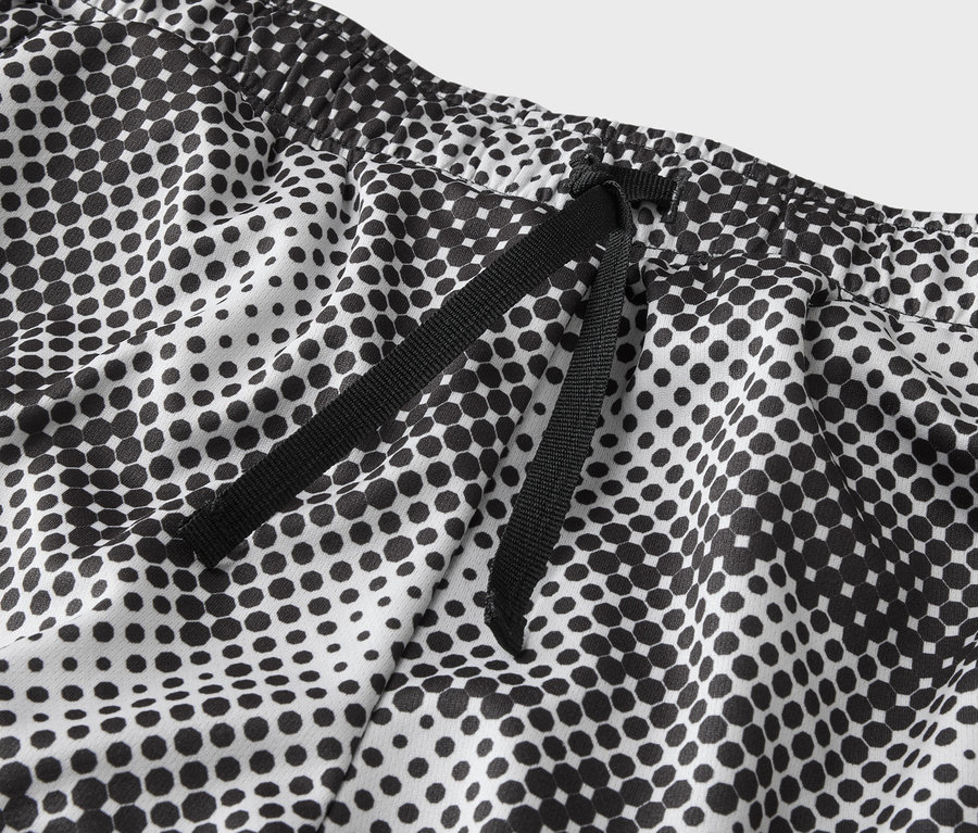 Gros plan sur la taille d'un pantalon blanc à pois noirs avec un cordon de serrage noir.