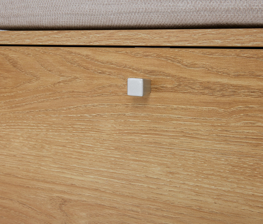 Gros plan sur une commode en bois marron clair avec un tiroir et une poignée carrée argentée.