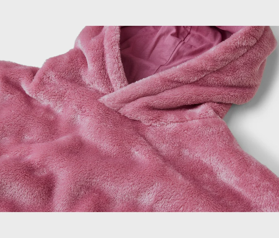 Gros plan d'un vêtement à capuche rose poudré et moelleux, montrant la texture douce du tissu et la doublure lisse à l'intérieur de la capuche.