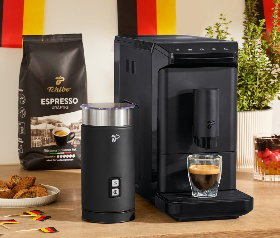 Une machine à café entièrement automatique « Esperto mini », un mousseur à lait électrique noir et 2 verres à double paroi pour expresso sont posés sur une table.