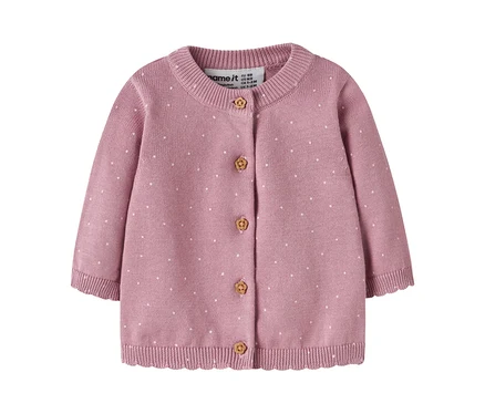 Cardigan bébé en tricot rose à pois blancs, col rond et manches longues. Il présente cinq boutons marron clair sculptés de fleurs et un ourlet côtelé festonné. Une étiquette de marque "name it" est visible.
