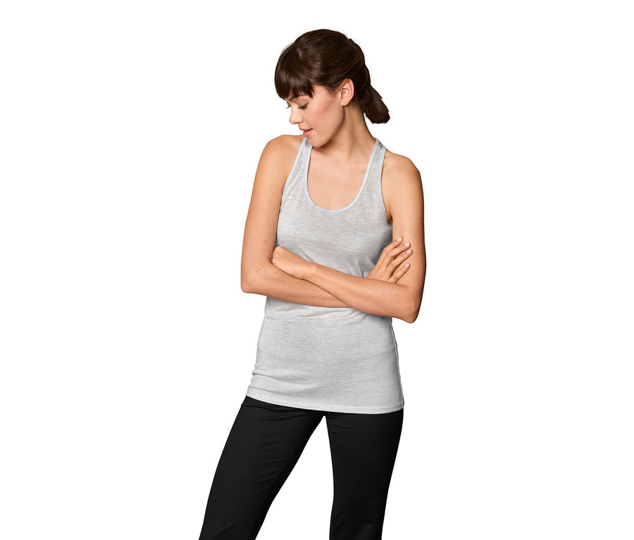 Femme les bras croisés portant un t-shirt de sport 2 en 1 et un pantalon noir.
