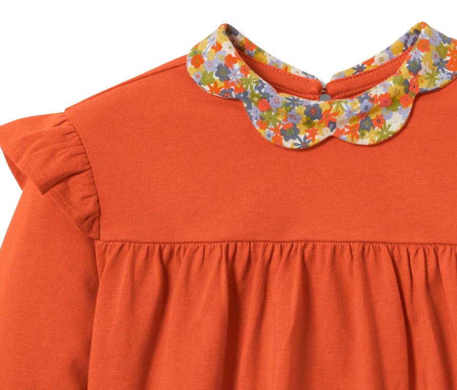 T-shirt à manches longues orange pour tout-petits avec un col fleuri et des volants aux épaules.