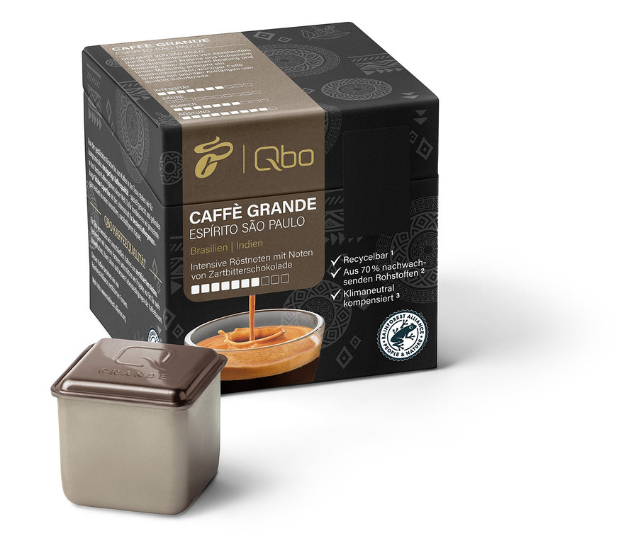 Un paquet de Qbo Caffè Grande ESPÍRITO SÃO PAULO et une capsule sont visibles. Les inscriptions sur l'emballage sont en allemand.