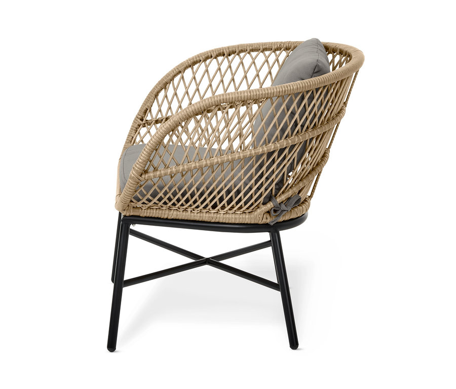 Gros plan sur un fauteuil de jardin « Boho » beige avec tressage en polyrotin et coussin gris sur un cadre métallique noir.
