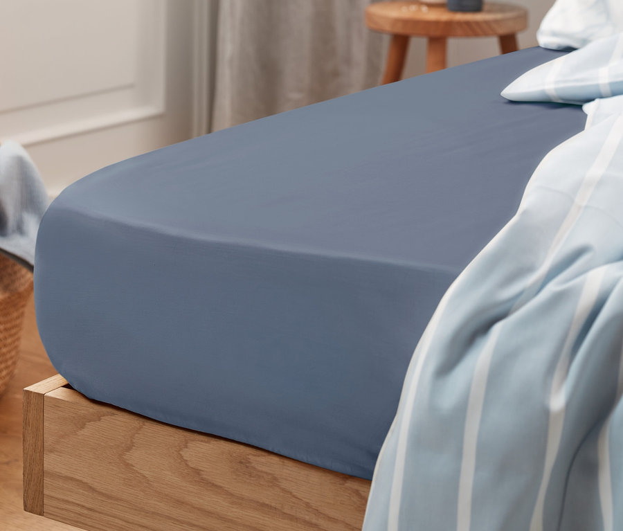 Drap-housse en jersey bleu de taille standard sur un lit.