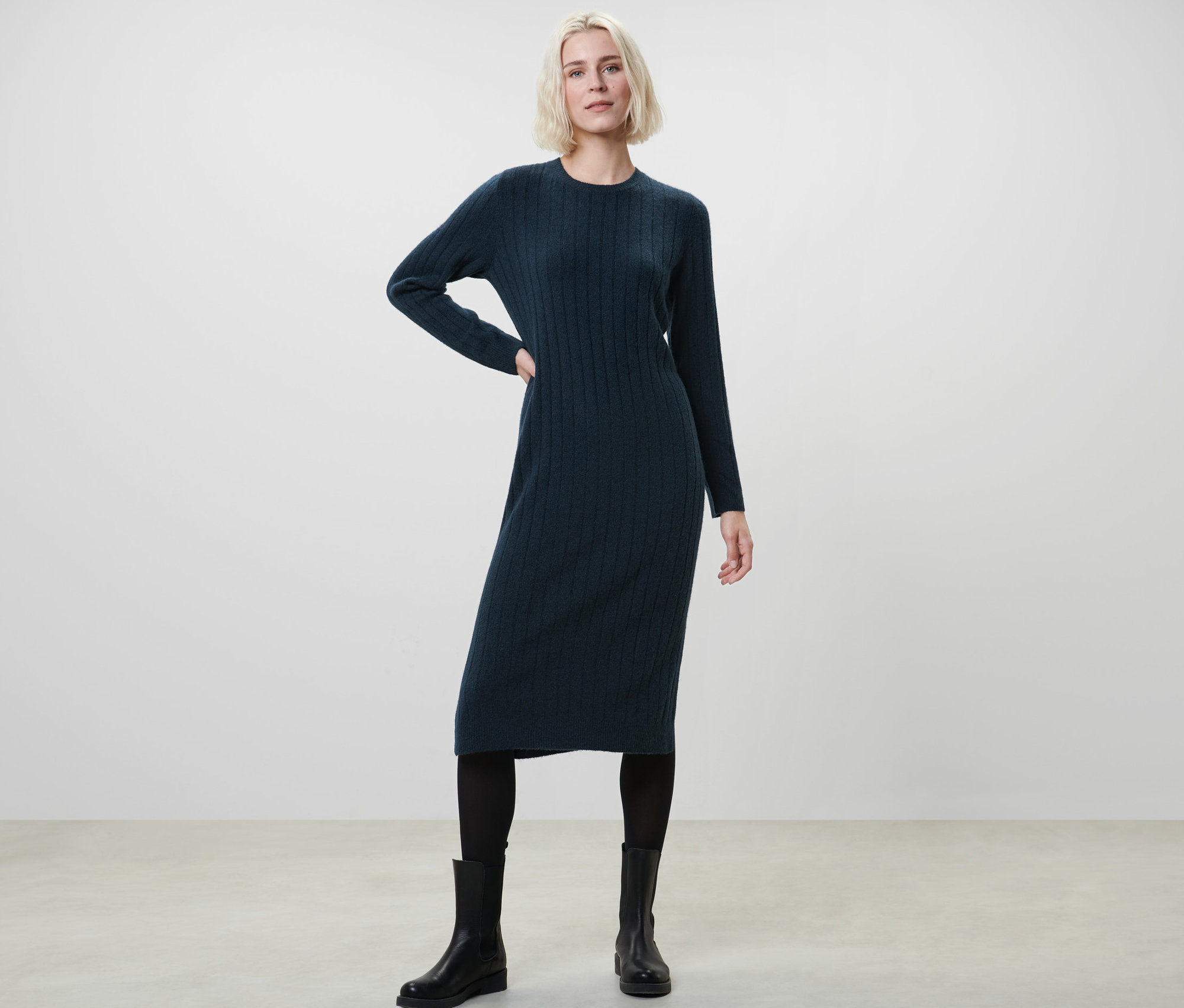 Femme posant dans une robe en tricot côtelée bleu foncé.