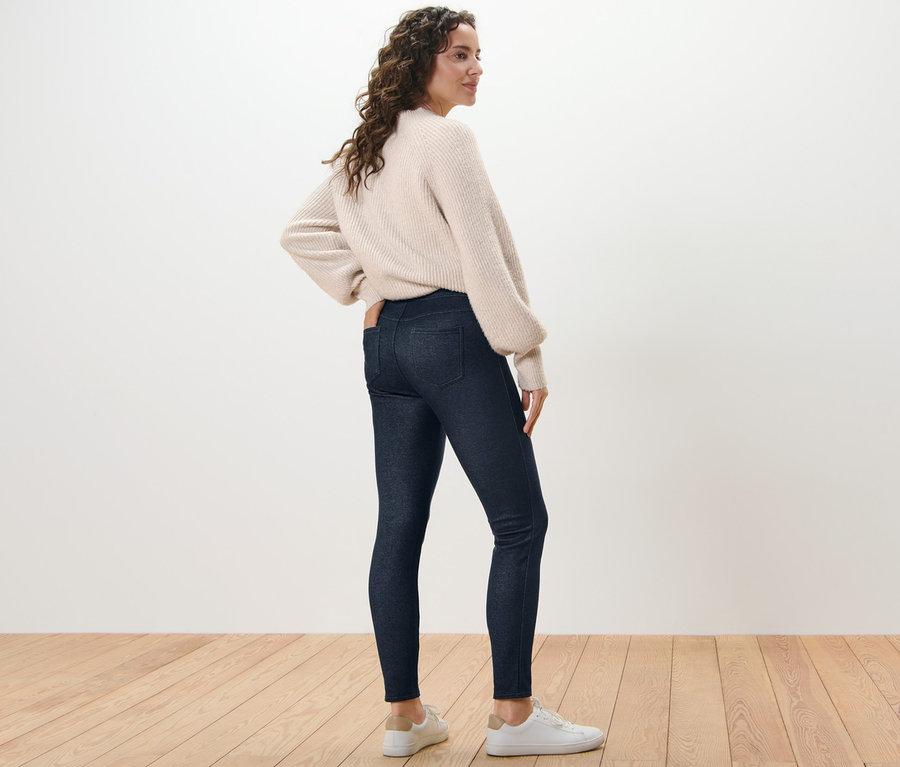 Femme posant en legging doublé à l’aspect jean et pull.