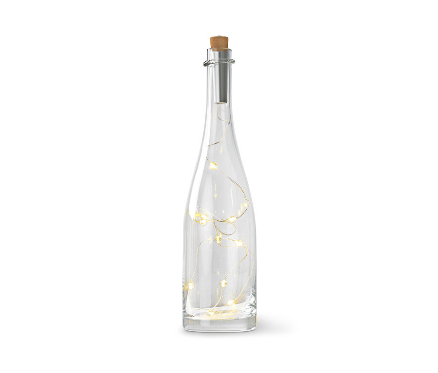 Une bouteille en verre transparent avec un bouchon de liège et une guirlande lumineuse à l'intérieur.