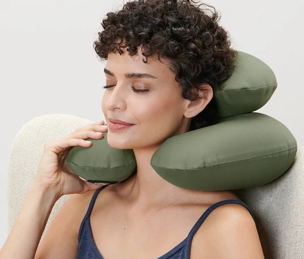 Femme assise dans un fauteuil utilisant un coussin gonflable pour la nuque.