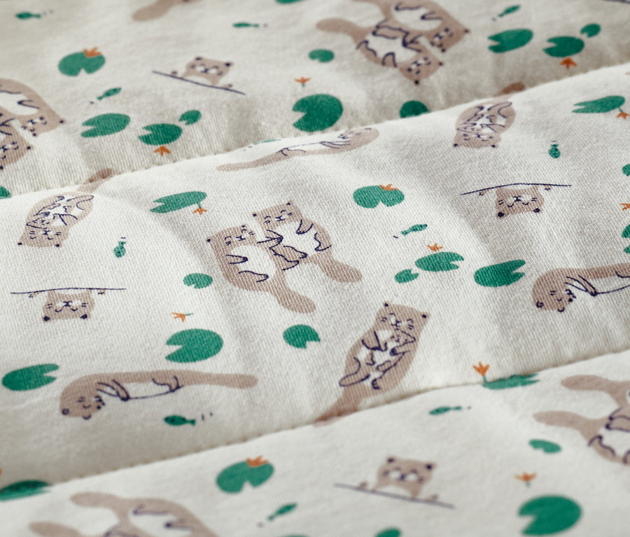 Tissu avec motif de loutres et de nénuphars.