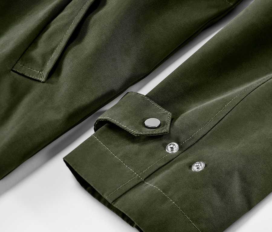 Gros plan sur une parka verte avec une poche et une manche avec des boutons-pression argentés.