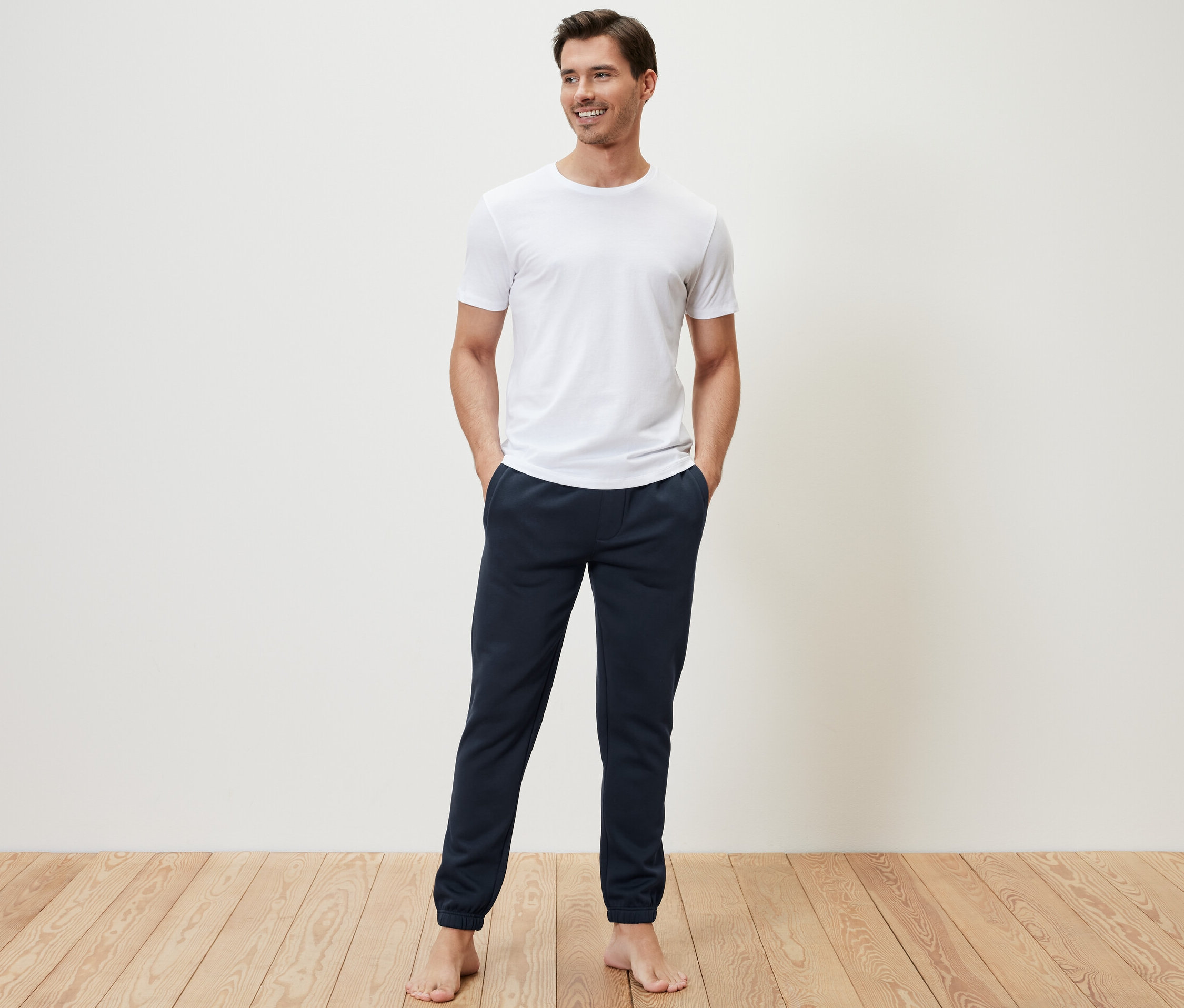 Un homme debout, les mains dans les poches de son pantalon en sweat.