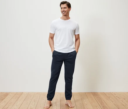Un homme debout, les mains dans les poches de son pantalon en sweat.