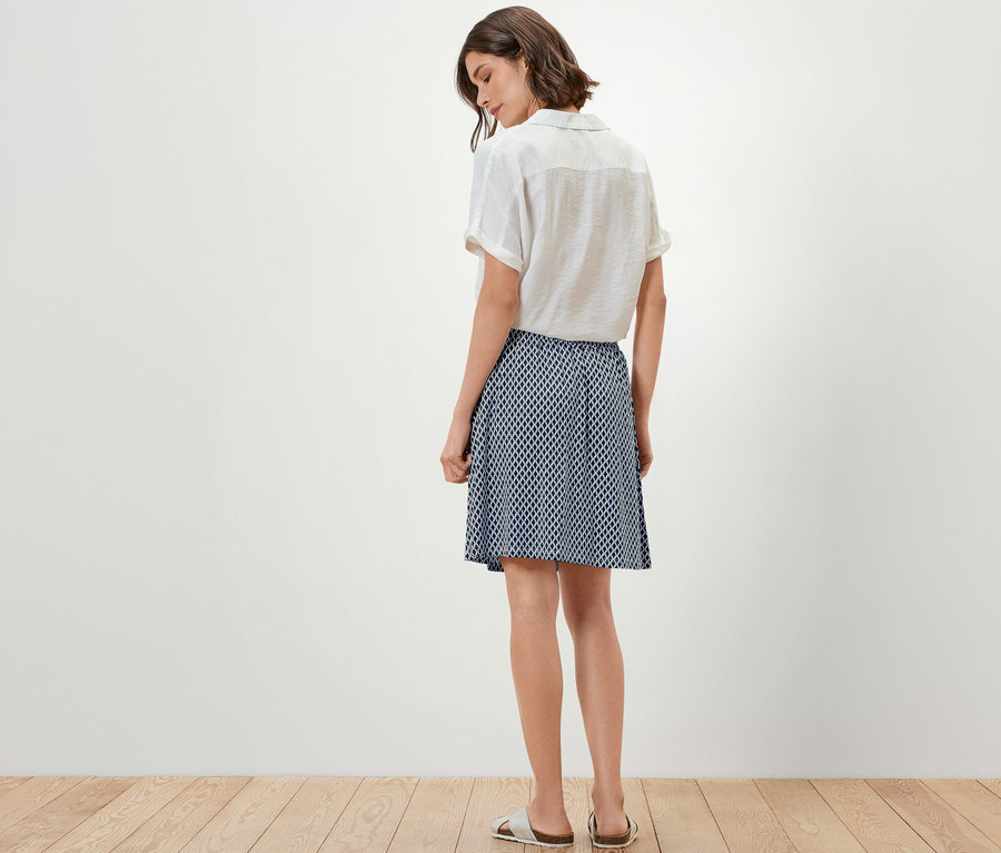 Une femme se tient dos à la caméra et porte un haut et une robe en jersey imprimée.