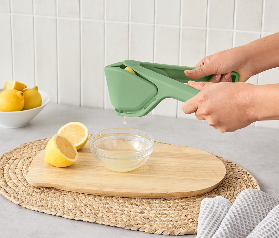 Une femme utilise un presse-agrumes compact pour presser un citron dans un bol.