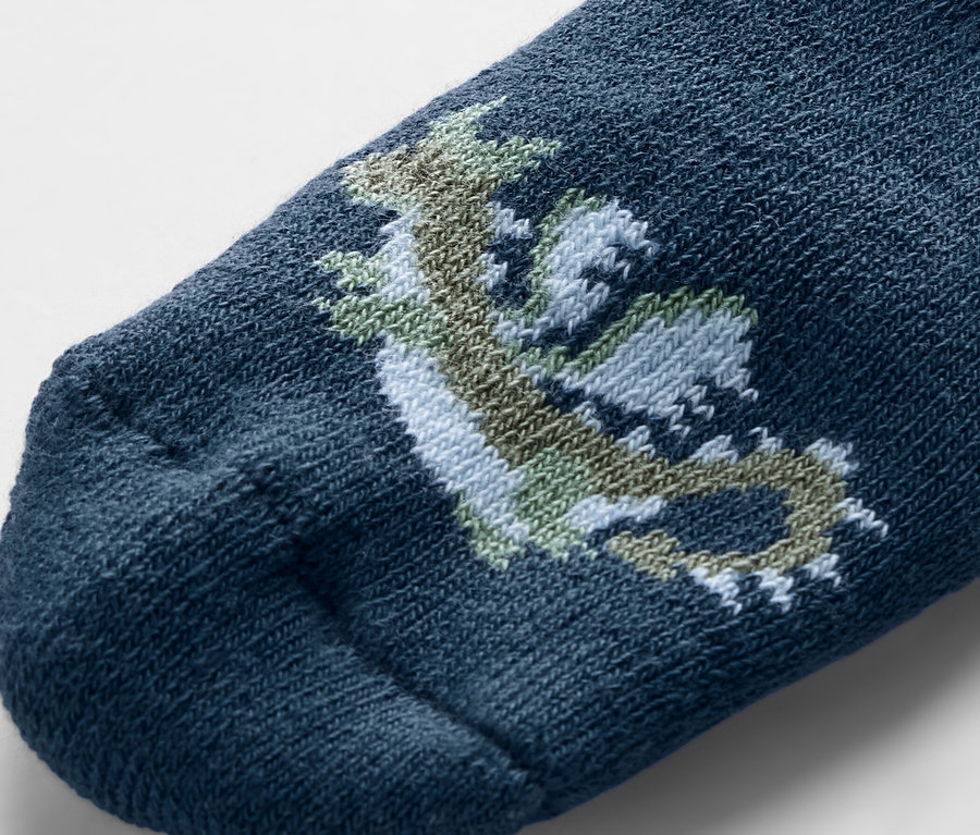 Gros plan d'une chaussette bleue pour bébé avec un dragon dessiné.