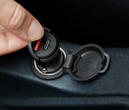 Une main insère un appareil de charge rapide pour voiture dans une prise.