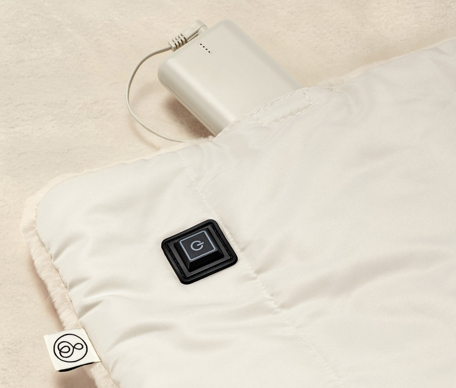 Vue détaillée d'un poncho chauffant à batterie avec bouton de commande et batterie connectée.