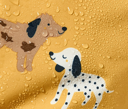 Gros plan sur une combinaison de pluie jaune avec des chiens de dessin animé et des gouttes d'eau.