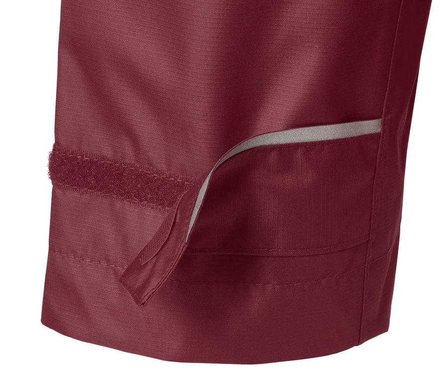 Gros plan sur une veste de pluie bordeaux avec une fermeture velcro visible.