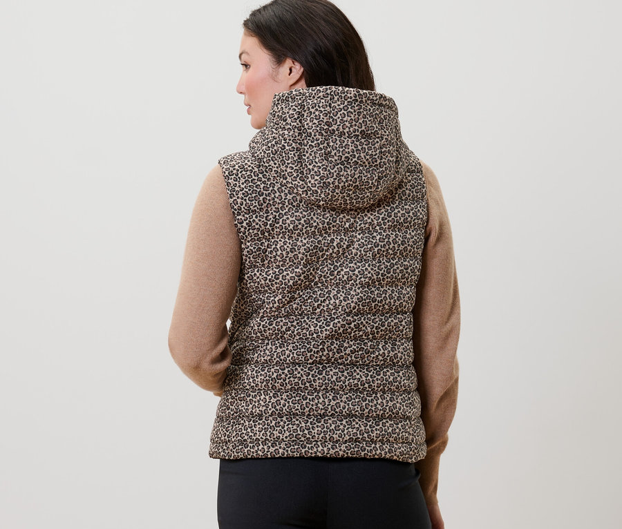 Une femme vue de dos porte un gilet sans manche matelassé imprimé à capuche.