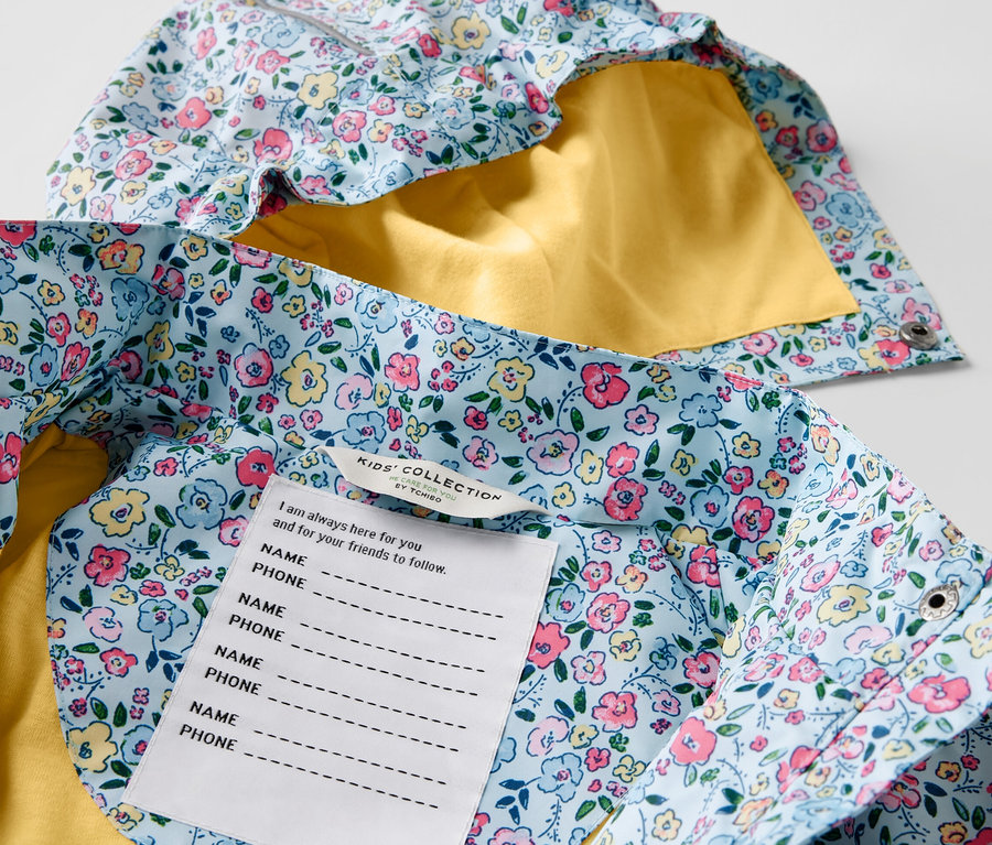 Gros plan sur une veste de pluie pour enfant à fleurs avec une doublure jaune.