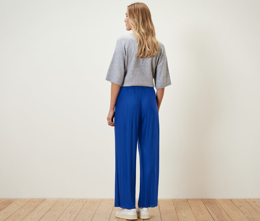 Femme portant un pantalon plissé bleu cobalt et un haut gris.