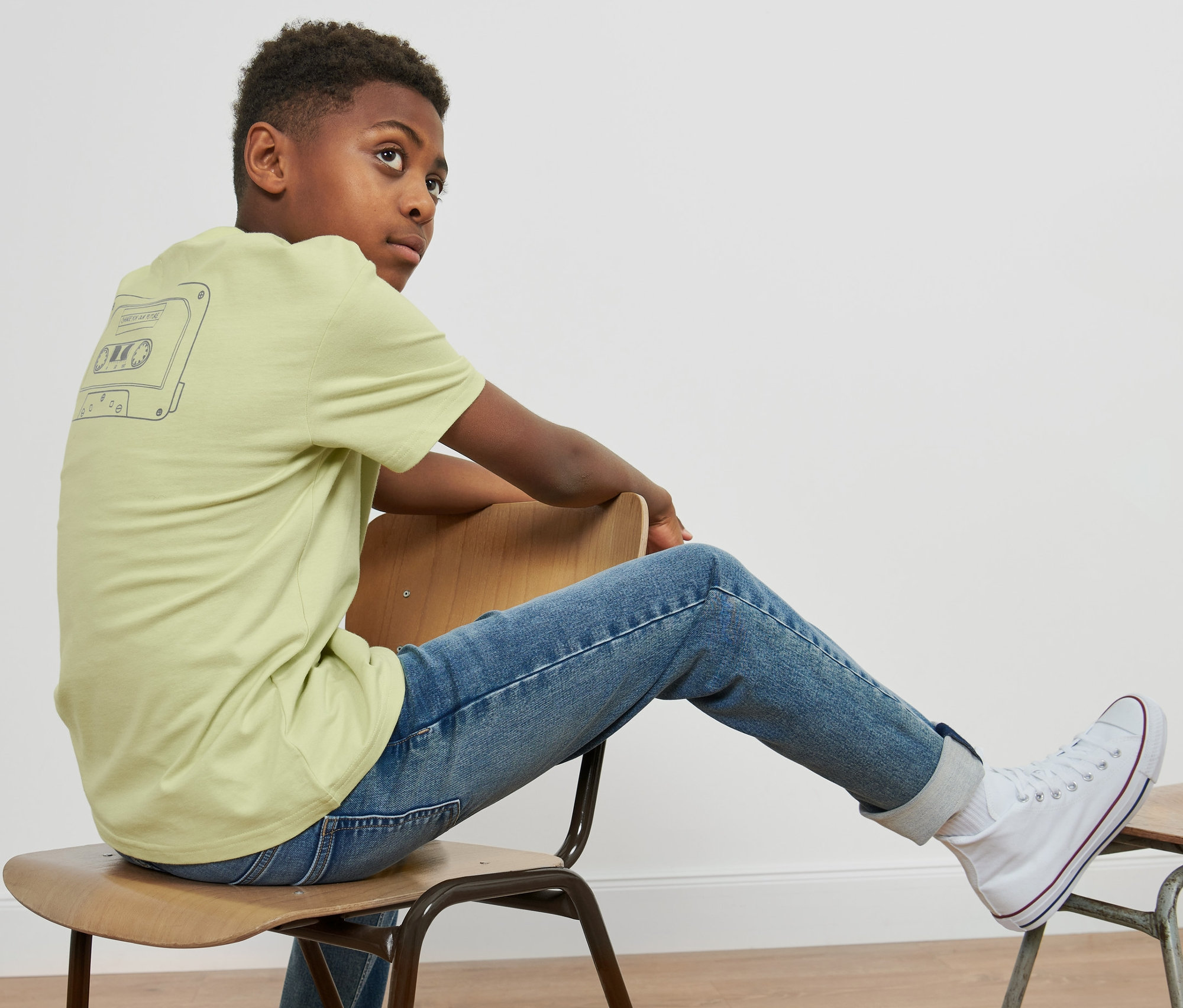 Garçon assis sur une chaise portant un t-shirt oversize enfant.