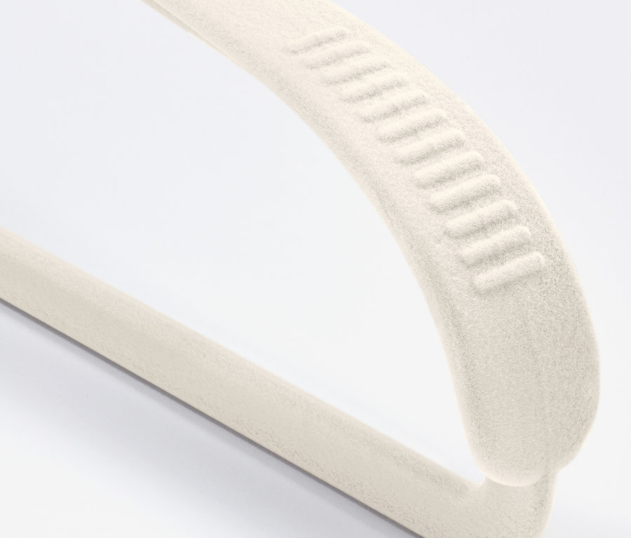 Gros plan d'un cintre en velours crème avec revêtement antidérapant sur fond blanc.