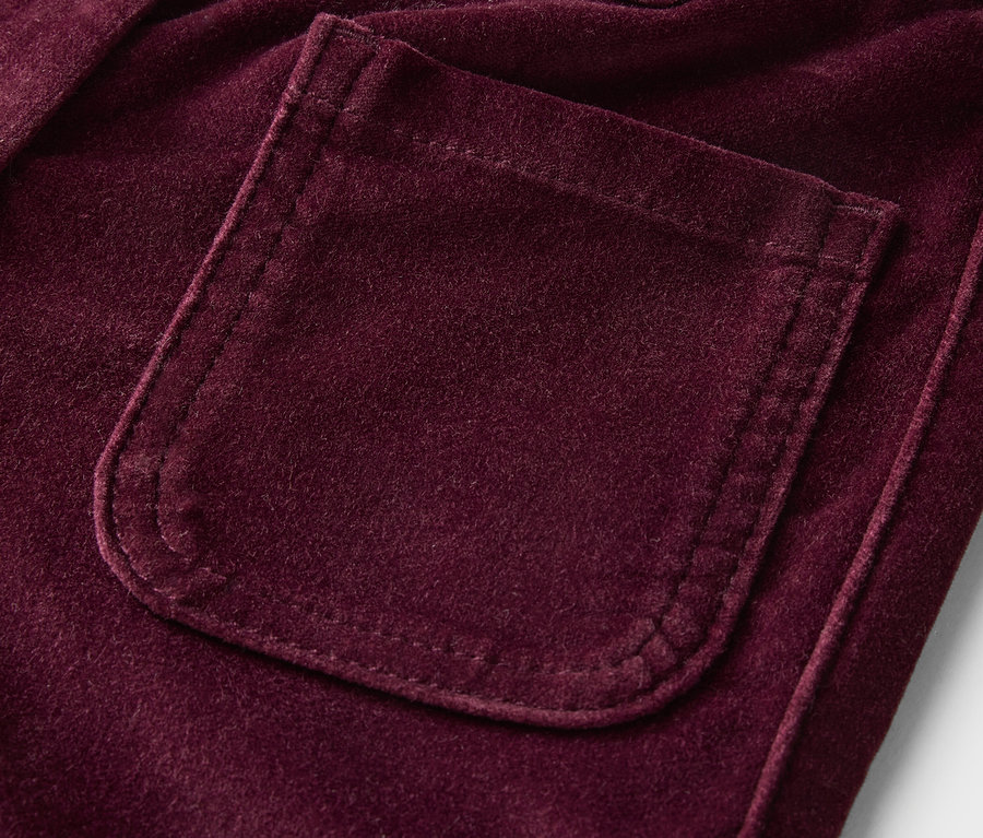 Détail d'un pantalon en velours violet avec une poche.