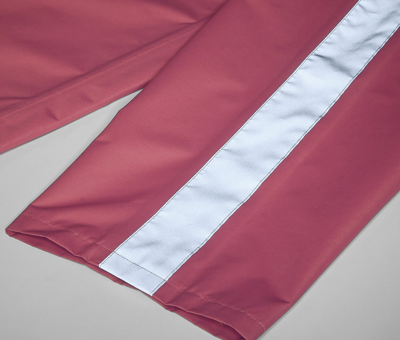 Gros plan sur un pantalon de pluie rose pour enfant avec une bande réfléchissante.