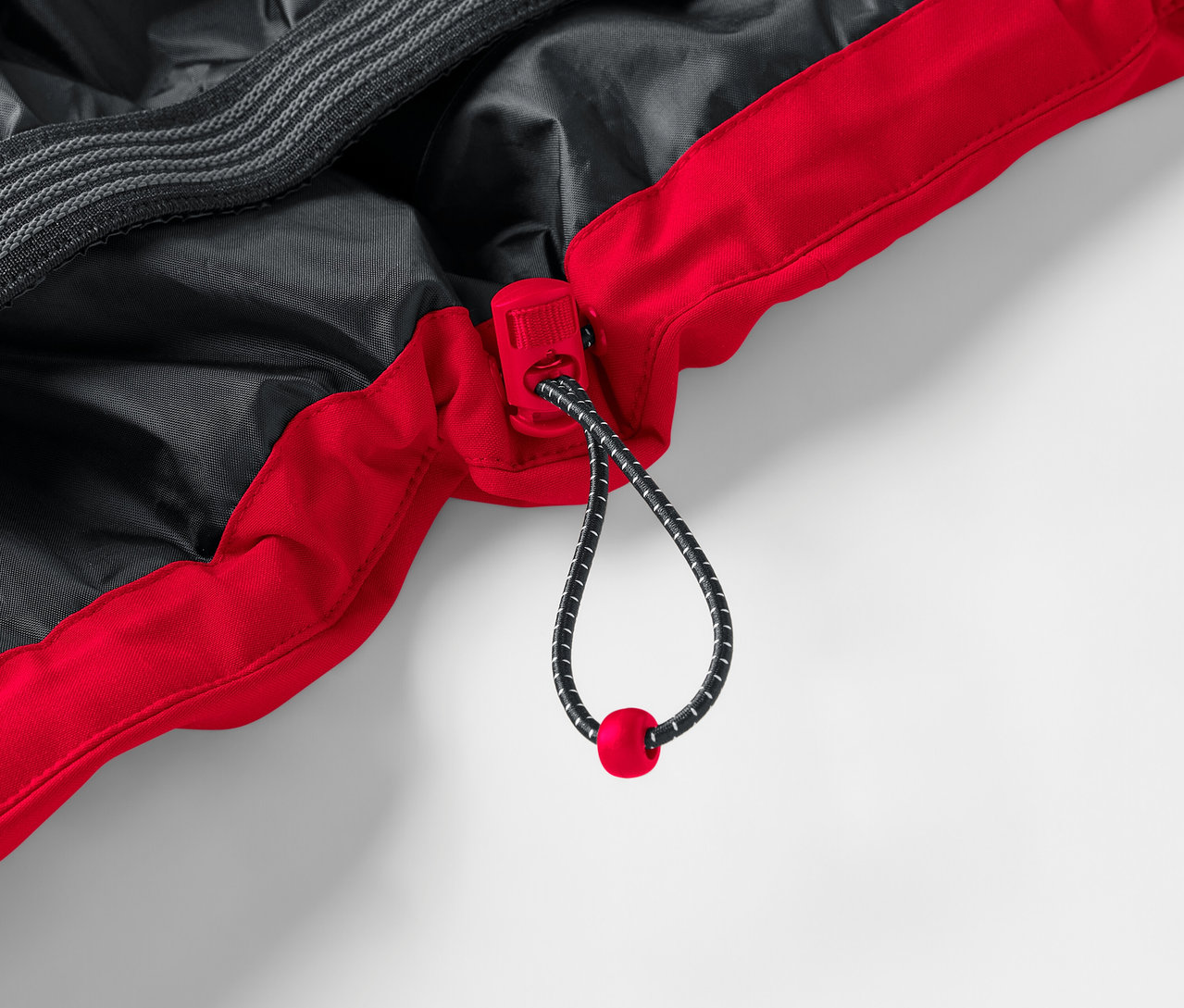 Détail d'une veste rouge et noire avec cordon de serrage.