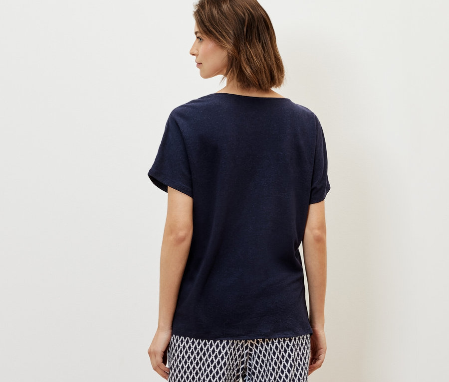 Une femme porte un t-shirt en lin mélangé bleu marine et un pantalon à motifs.
