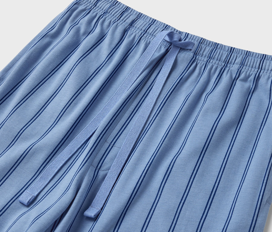 Gros plan sur un pantalon de pyjama bleu rayé avec une taille élastique et un cordon de serrage.