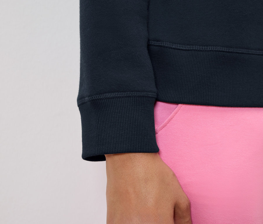 Gros plan sur la manche d'un sweat-shirt bleu marine et une partie d'un pantalon rose.