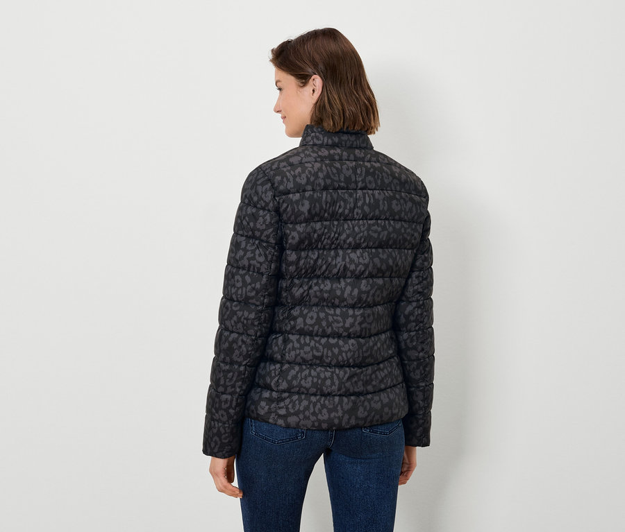Une femme, vue de dos, porte un blouson matelassé noir à imprimé animalier et un jean.