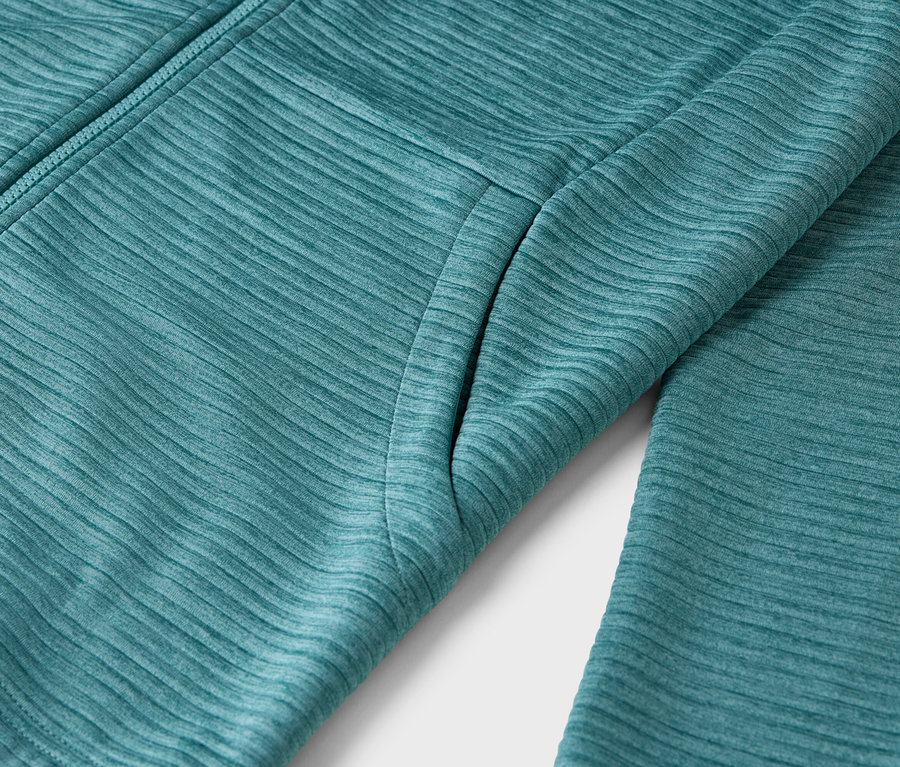 Gros plan sur une veste textile turquoise avec fermeture éclair et poche.
