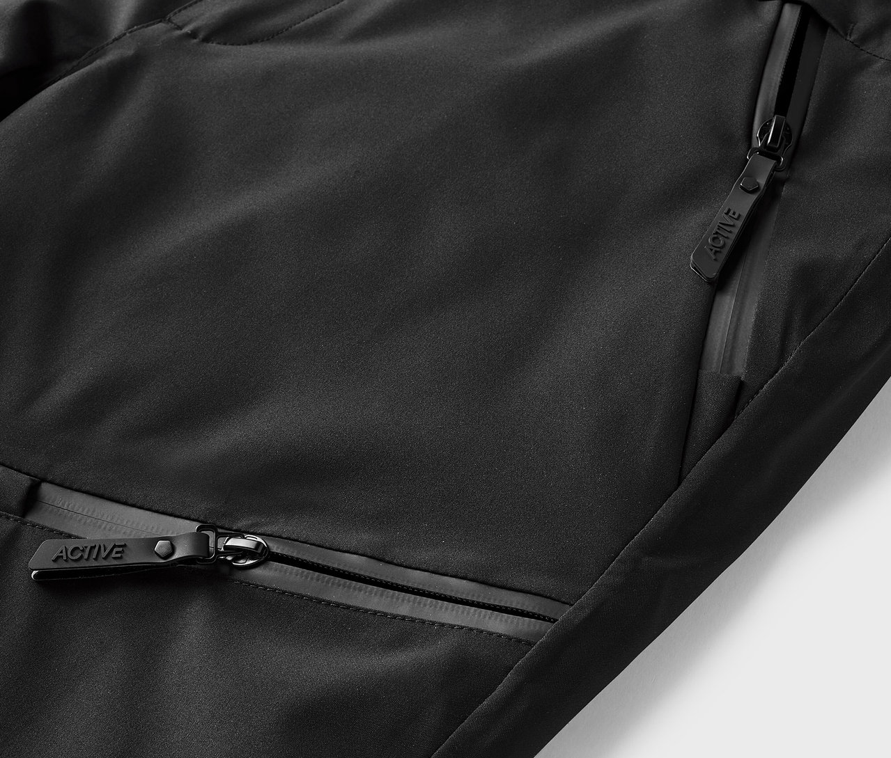 Gros plan de vêtements de sport noirs avec poches zippées.