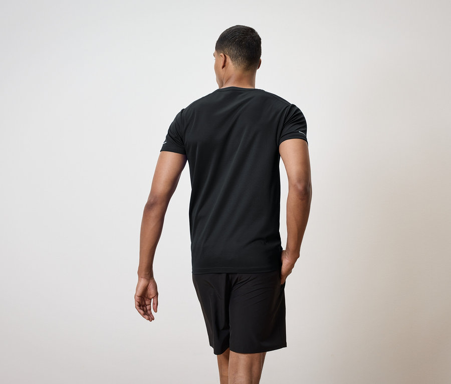 Homme vu de dos portant un t-shirt noir et un short.