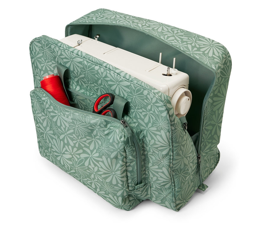 Sac de machine à coudre ouvert à motif floral avec une machine à coudre, une bobine de fil rouge et des ciseaux à l'intérieur.