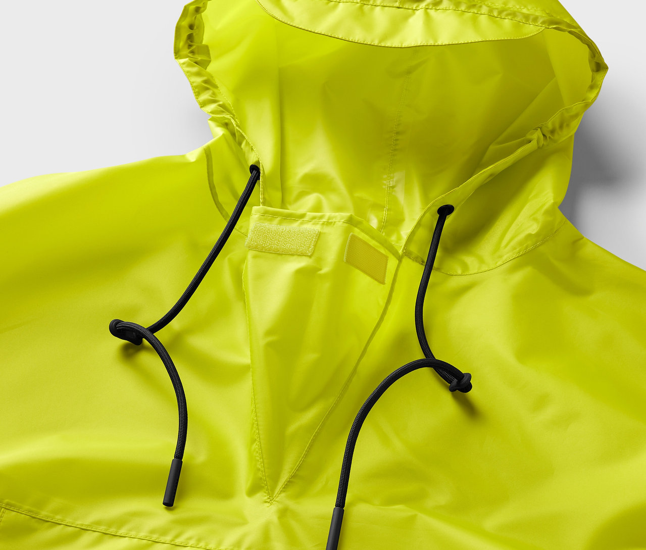 Gros plan sur un poncho de pluie jaune néon avec capuche et cordons de serrage noirs.