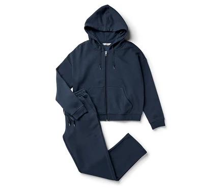Un sweat à capuche zippé bleu marine et un pantalon de survêtement posés sur un fond blanc.