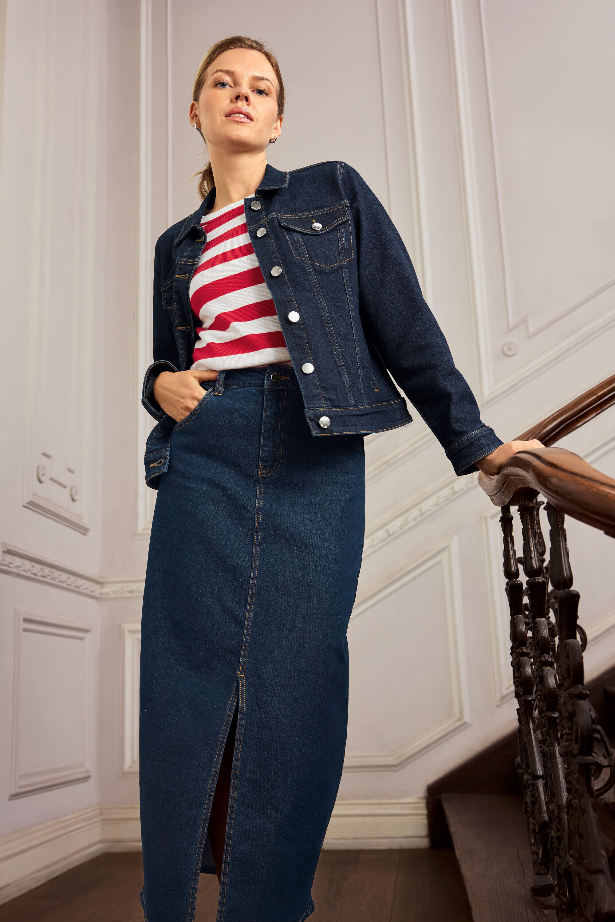 Femme posant dans un escalier avec une veste en jean et une jupe en jean. Elle porte des créoles en argent 925 hexagone.