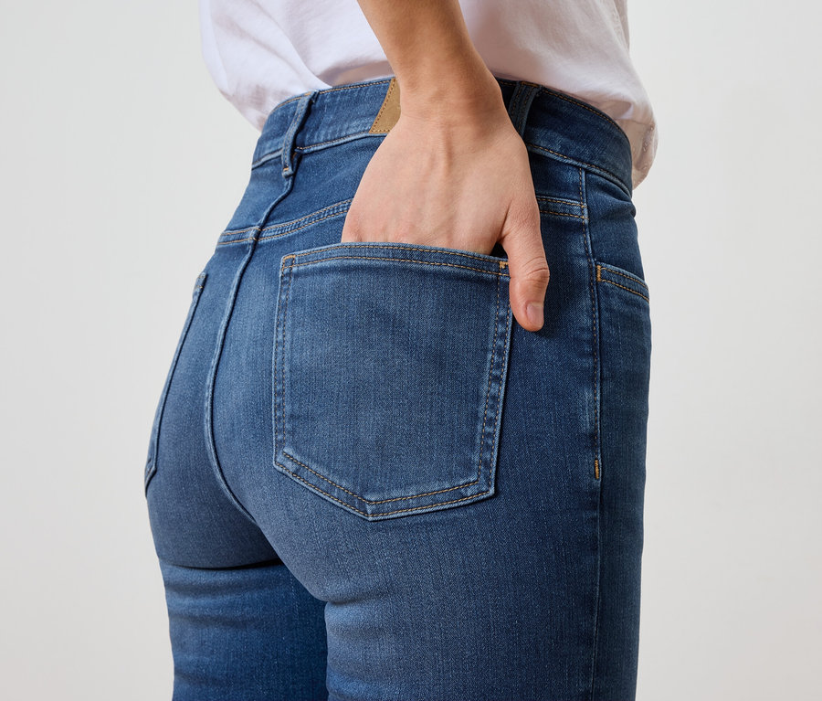 Femme avec la main dans la poche arrière d'un jean bleu.