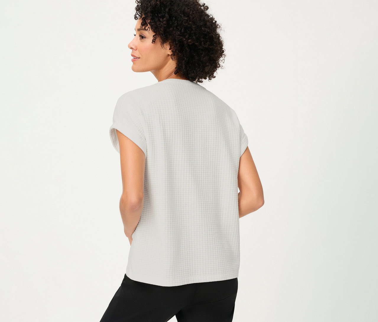 Femme de dos portant un t-shirt Olsen structuré avec des boutons et un pantalon noir.