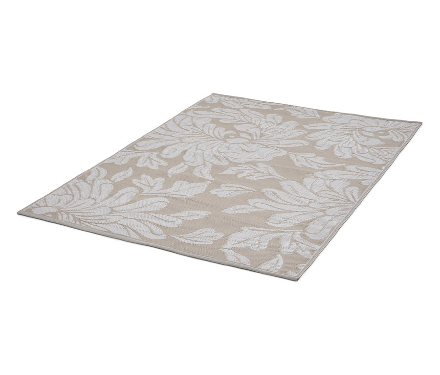 Un tapis beige avec un motif floral blanc est posé sur le sol.