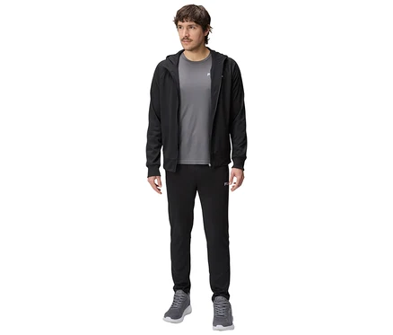 Homme portant un survêtement noir à capuche, un t-shirt gris, un pantalon de survêtement noir et des baskets grises.
