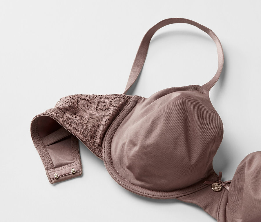 Gros plan d'un soutien-gorge mauve avec des détails en dentelle sur un fond blanc.