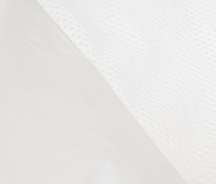Gros plan d'un tissu blanc et lisse bordant un tissu en maille blanche.